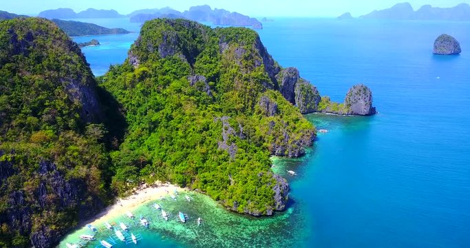 Exotic Beach Cove With Catamaran Style Boats On Rocky Tropical Island - El Nido, Palawan, Philippines - Aerial View