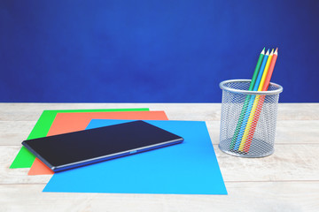 Colorful stationery and tablet on wooden desk