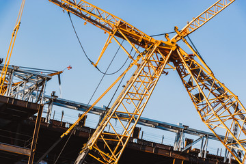 Fototapeta na wymiar arms of yellow tower crane constructing building