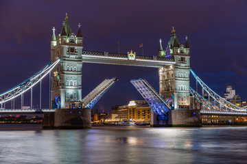 The iconic Tower Bridge in London at night, beautifully illuminated and with raised bascules for river traffic