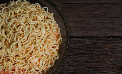 Instant noodles in bowl on wooden background.