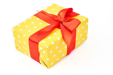 Gift box with red satin bow. Yellow dotted box with present isolated on white background. Beautifully packed New Year gift.