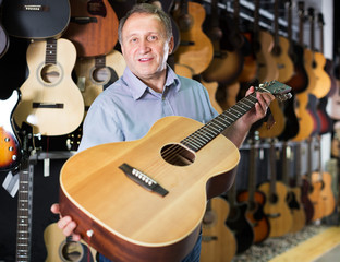 Mature man choosing acoustic guitar