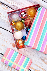 Striped gift box and Christmas decorations. Christmas festive baubles and gift box on old wooden background, top view.