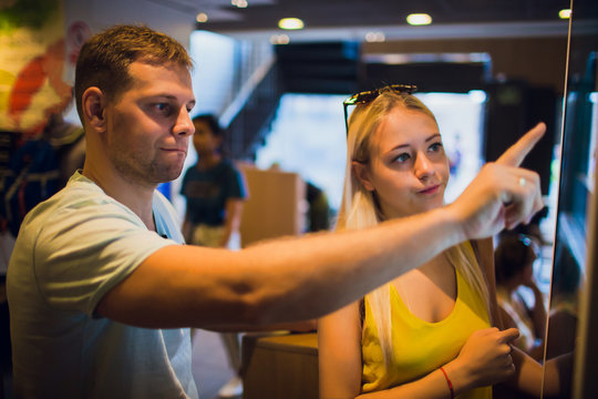 Group People, Friends Ordering Food At The Touch Screen Self Service Terminal By The Electronic Menu In The Fastfood Restaurant