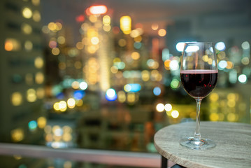 red wine in the glass on the table with the city lights bokeh in the background 