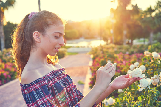 Girl taking smartphone photo to rose flower