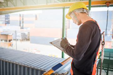 Obraz premium Industrial Worker taking notes with safety protective harness, industrial work context 