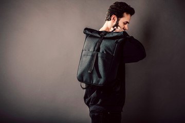 Stylish young guy wearing black blank  and backpack, horizontal studio portrait
