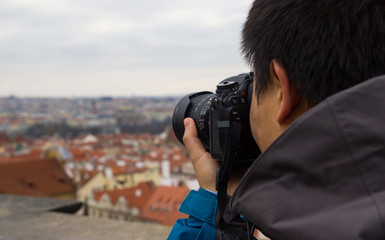 Man looking into DSLR camera and taking photo of Prague landscape in Europe