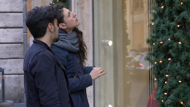 Christmas shopping.Young couple in front of a shop window