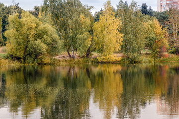 Fototapeta na wymiar Fall in the park. Autumn trees reflected in the pond of Pokrovskoe-Streshnevo city park, Moscow, Russia. Calm and tranquility.