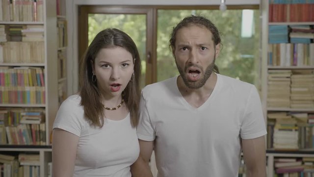 Jaw dropping reaction from teenage couple watching something scary and unbelievable looking thrilled and astonished with open mouth