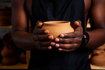 Fototapeta na wymiar happy African American businessman potter male owner making clay sculpture pot cup vase at workbench in workshop studio . creativity and creative china shop merchant