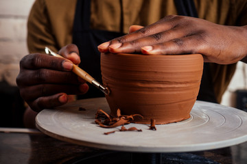 young and happy latino american businessman creating molds a handmade clay hands pot vase in...