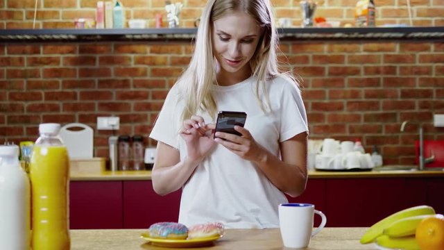 Woman eats breakfast and uses her mobile phone