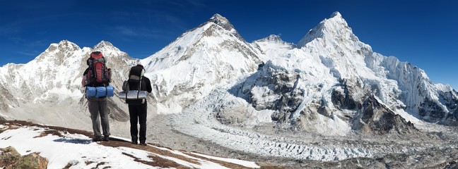Panoramic view of Mount Everest with two tourists - obrazy, fototapety, plakaty