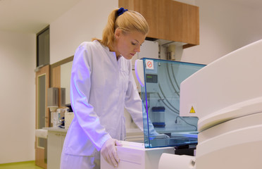 A young woman takes up her duties as  lab technitian. She wears a white smock to work with while analyzing.
