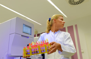 A young woman takes up her duties as  lab technitian. She wears a white smock to work with while...