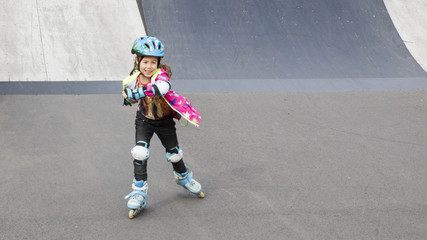 Little girl riding on roller skates in a helmet and knee pads
