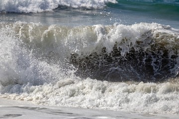 close up of a foamy wave crashing on to the shore