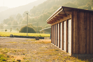 Wooden garage for many cars in countryside at sunny day with mountains in background