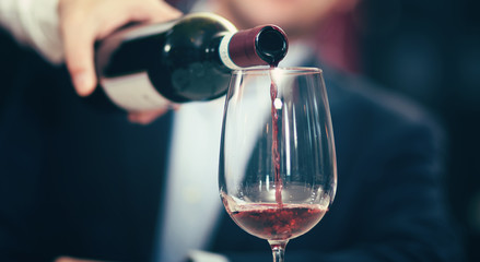 Waiter pouring red wine