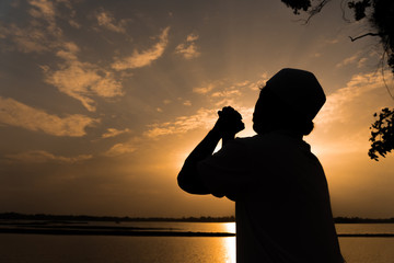 Silhouette Young asian muslim man praying on sunset,Ramadan festival concept