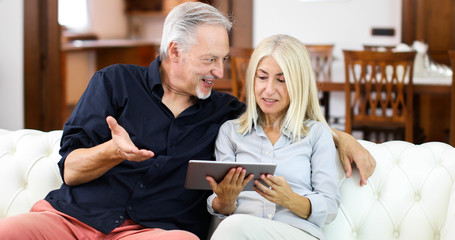 Portrait of a smiling mature couple using digital tablet on sofa at home