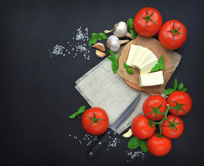 Fresh feta cheese with tomatoes,greens on wooden serving board over wooden background. Food Ingredients, view from above. Healthy food.Top view.