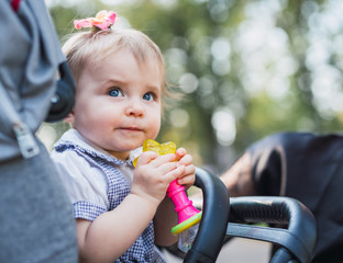 Cute baby holding toy in carriage