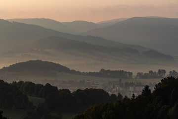 Obraz premium Dramatic mountain landscape before the storm - heavy gray clouds float above the green wooded hills to the horizon.