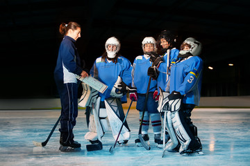 Female coach reviewing game plan with hockey team - Powered by Adobe