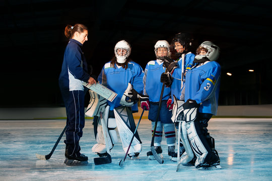 Female coach reviewing game plan with hockey team