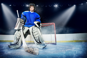 Naklejka premium Young goalie in the spotlight of ice hockey arena
