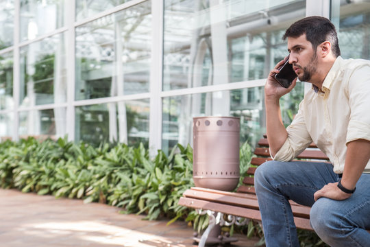 Man Sitting On A Bench Talking On The Phone