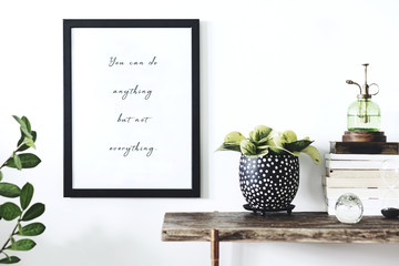 Fototapeta premium Stylish and modern scandinavian room with wooden console, mock up poster frame, books, green sprinkler and beautiful plants. Design composition of home interior.