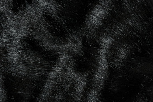 Highly detailed background texture of black fur made of synthetic animal long hair.