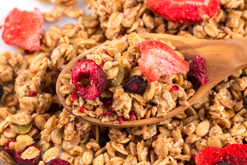Fototapeta premium Muesli oat cereals close up background with dry fruits in wooden spoon