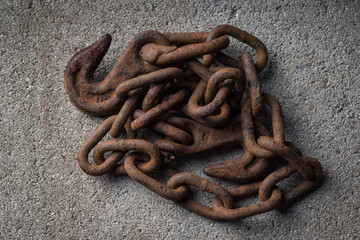 A pile of rusty metal chain is displayed on a stone slab