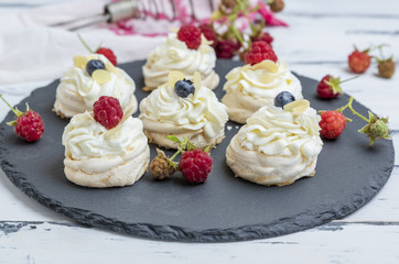 baked round meringues with whipped cream on a black graphite board