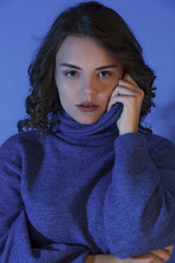 blue sweater on brunette model in studio on blue background