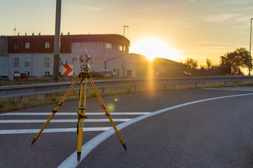 Surveyor equipment (theodolit or total positioning station) on the construction site of the motorway or road during sunrise