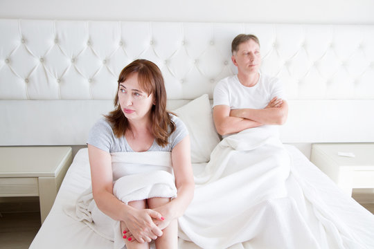 Family life concept.Problems in relationships. Middle age couple in bedroom. Man and woman in bed. Quarrel and upset emotions. Selective focus