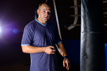 beginner boxer portrait at punching bag on a dark background