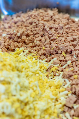 A Pile of Small Cutted Pieces of Boiled Eggs with Chopped Ham in Background