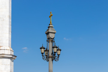 Fototapeta na wymiar Tall, church, bronze lantern against the blue sky. Orthodox cross on a beautiful lantern. Landmark of Moscow, blue sky with clouds.