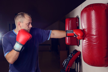 male boxer practicing punches on a punching bag in the gym