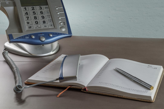 Telefon mit einem Notizbuch auf einem Schreibtisch.