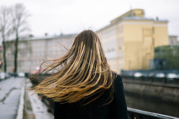 Fototapeta na wymiar Girl with long hair in the winter windy city